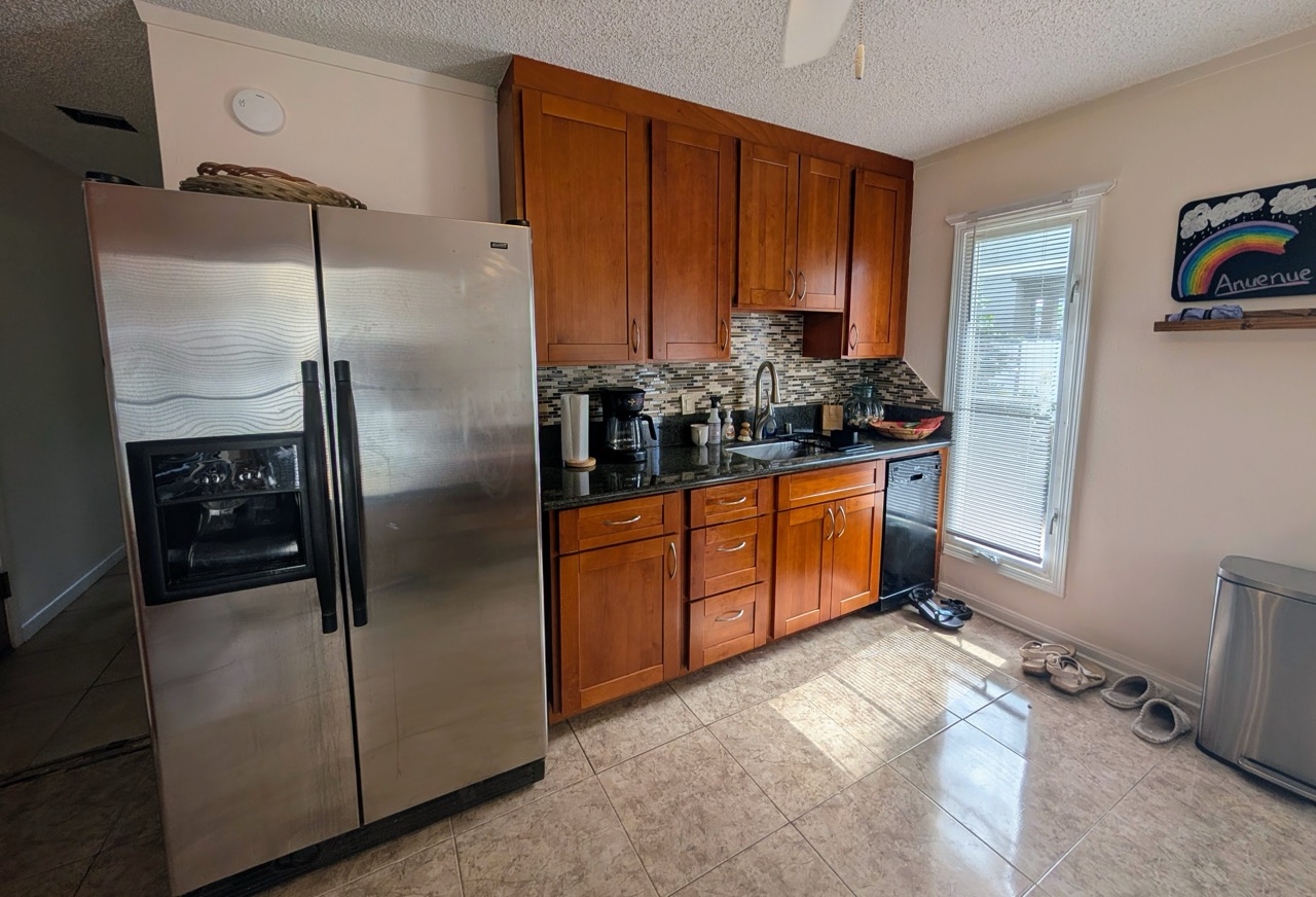 Hauʻula Hideaway kitchen view featuring stainless steel fridge, sink area, and wood cabinetry
