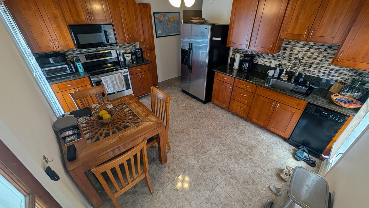 Full kitchen at Hauʻula Hideaway with wood cabinetry, dining set, and modern appliances