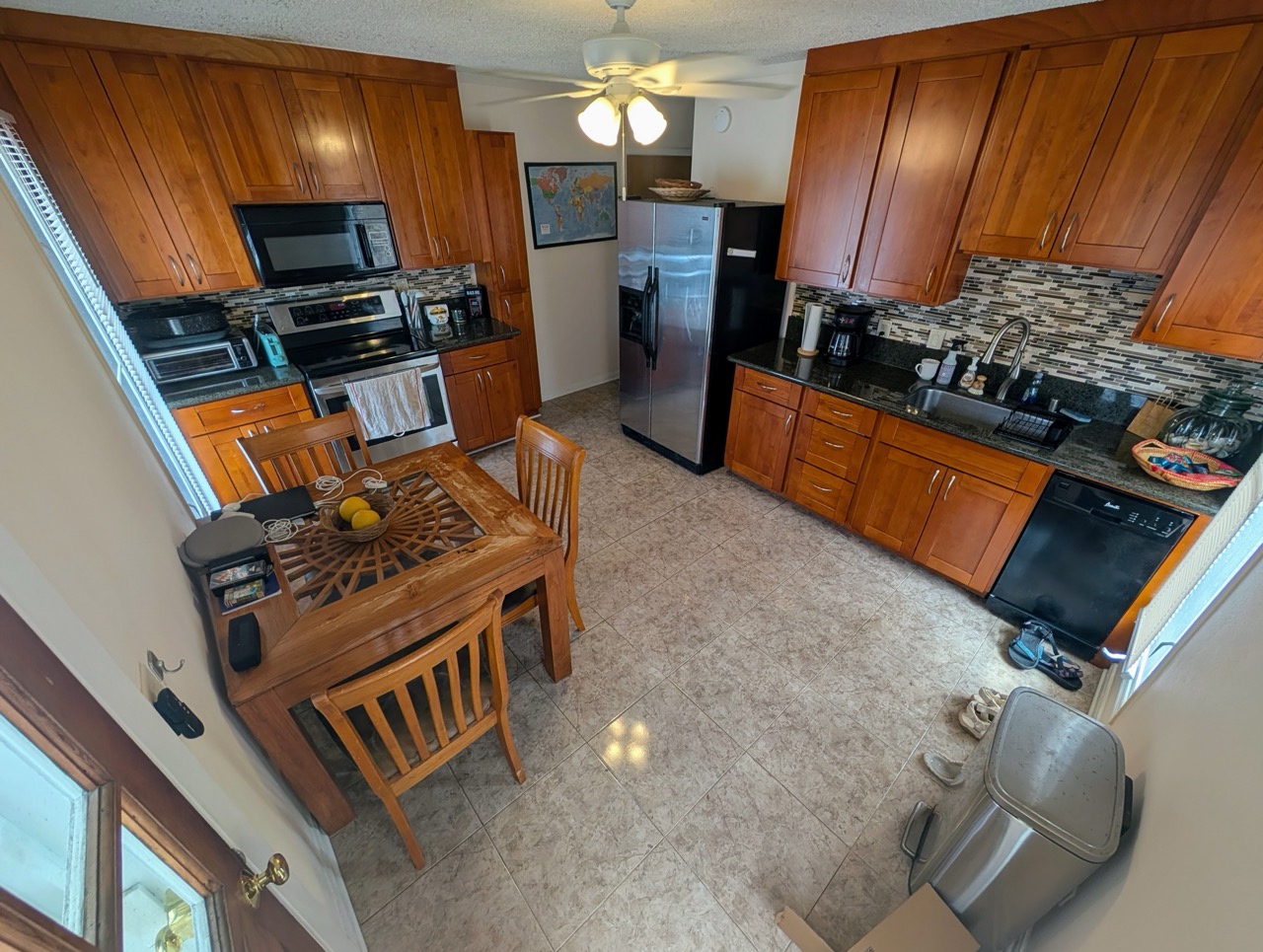 Full kitchen at Hauʻula Hideaway with wood cabinetry, dining set, and modern appliances